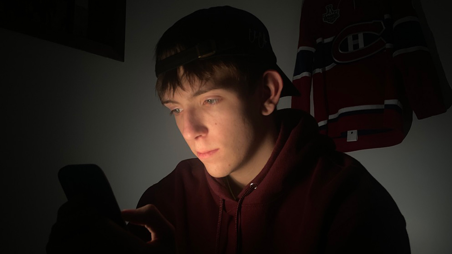 Un jeune Québécois consulte des plateformes de paris sportifs, un phénomène amplifié par les influenceurs et réseaux sociaux.